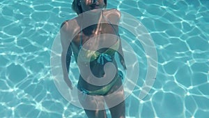 Pretty woman swimming underwater in pool