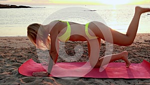 Pretty woman in swimsuit doing yoga on the ocean coast. Silhouette of young girl doing exercises