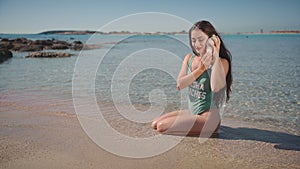Pretty woman in swimsuit listening to seashell on seaside. Spa, travel, luxury, lifestyle, blogger, beauty concept