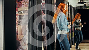 Pretty woman trying on jeans jacket in fitting room of store