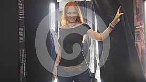 Pretty woman trying on jeans jacket in fitting room of store