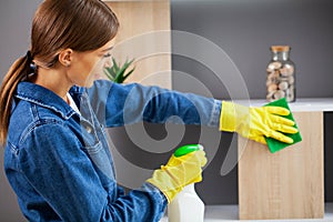 Pretty woman in uniform with supplies cleaning in office