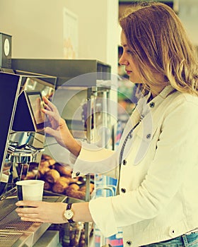 Pretty woman using coffee vending machine.