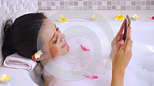 Pretty woman using mobile phone on bathtub