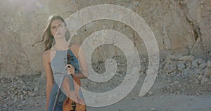 Pretty woman with violin in hand looks at the sky thoughtfully on nature