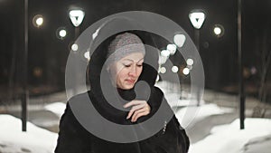 Pretty woman walking along the black fur coat. Outdoor. Girl walks on a winter night among the street lights of the city