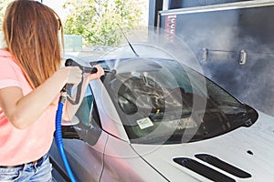 Pretty Woman Washing Her Car With High Pressure Washer At Self-Serve