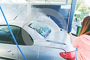 Pretty Woman Washing Her Car With High Pressure Washer At Self-Serve Car