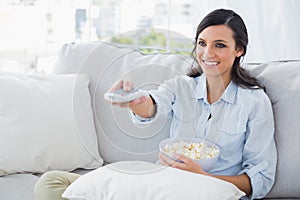 Pretty woman watching tv eating popcorn