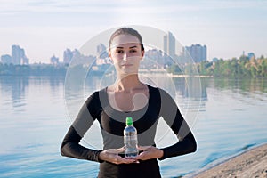 Pretty woman with water bottle at river and city backround