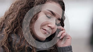 Pretty woman with wavy hair in city at snowy weather, winter portrait, closeup view of face no makeup