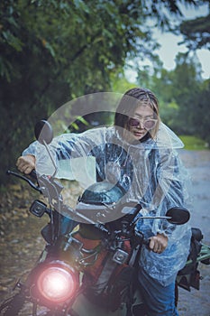 pretty woman wearing plastic rain clothes riding small enduro motorcycle