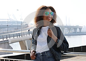 Pretty woman wearing sunglasses with perfect teeth and dark clean skin having rest outdoors