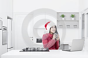 Pretty woman wears Santa hat in the kitchen