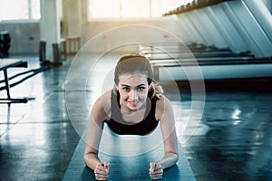 Pretty woman is working out in fitness gym., Attractive young woman is planking push-up exercise in front of treadmill machine., photo