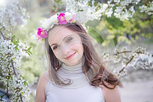 Pretty woman with wreath among apple blossom