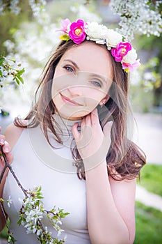 Pretty woman with wreath among apple blossom