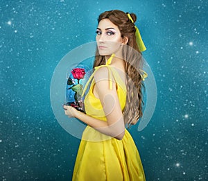 Pretty woman in the yellow long dress closeup with red rose in her hands. Beauty and the beast cosplay art processing