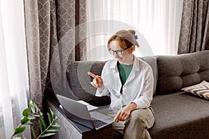 Pretty womanusing laptop elearning or remote working at home office looking at laptop computer watching webinar