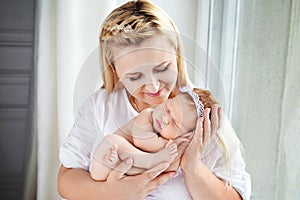 Pretty woman holding a newborn baby girl in her arms. Happy mother and her slipping newborn baby.  Happy family concept