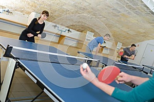 Pretty woman playing ping-pong with friends