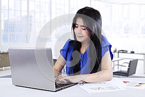 Pretty worker uses laptop in workplace