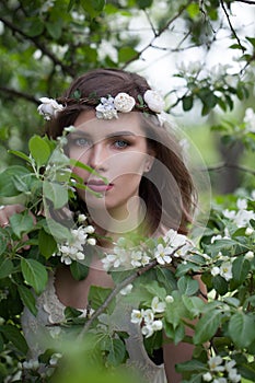 Pretty young adult woman female model with clean fresh skin, make-up and brown hair in blossom garden on green leaves background