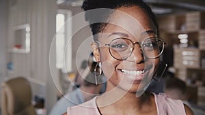 Pretty young African American happy female leader in glasses smiling at camera in modern office co-working background 4K