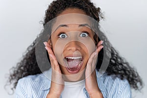 Pretty young african american woman looking at camera with surprised expression over white background