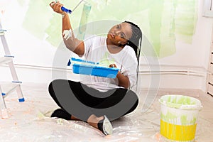 Pretty young african american woman with painting roller indoors. Redecoration, renovation, apartment repair and