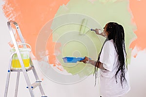 Pretty young african american woman with painting roller indoors. Redecoration, renovation, apartment repair and