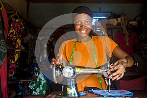Pretty young african female tailor smiling while working with her sewing machine