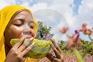 pretty young african lady enjoying a delicious slice of watermelon fruit outside