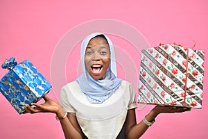 pretty young african woman holding gift boxes smiling and feeling excited