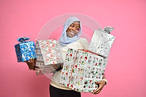 pretty young african woman holding a lot of gift boxes feeling happy and excited