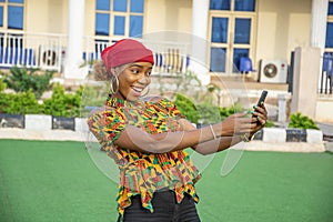 Pretty young African woman smiling and using her mobile phone outdoors