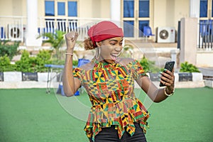 Pretty young African woman smiling and using her mobile phone outdoors