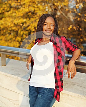 Pretty young african woman wearing a red checkered shirt in evening