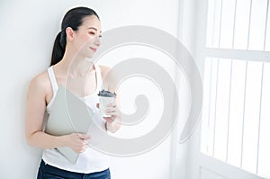 Pretty young asian business woman holding a cup of coffee and document files. Isolated Studio portrait smiling on white background