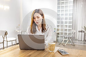 Pretty young asian business woman using laptop in modern cafe.