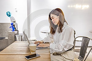 Pretty young asian business woman using laptop in modern cafe.