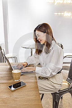 Pretty young asian business woman using laptop in modern cafe.
