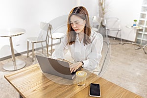 Pretty young asian business woman using laptop in modern cafe.