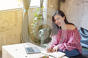 Pretty young asian business woman using laptop in modern cafe.