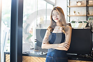 Pretty young asian waitress standing arms crossed in cafeteria.Coffee Business owner Concept.  barista in apron smiling at camera