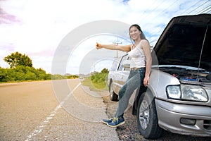 Pretty young Asian woman with hand up calling passing car.