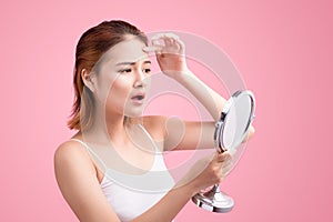 Pretty young asian woman holding a mirror, touch and worrying ab