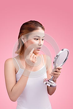 Pretty young asian woman holding a mirror, touch and worrying ab