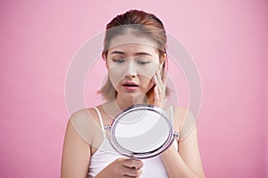 Pretty young asian woman holding a mirror, touch and worrying ab