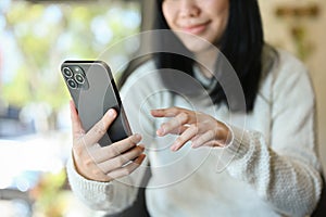 Pretty young Asian woman using her smartphone, chatting with her friends. cropped image